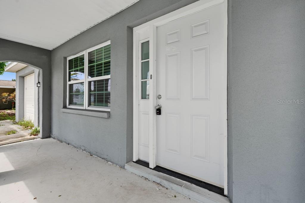 A gray exterior wall features a white front door with a sidelight and a window — 9517 MARLINTON LANE, PORT RICHEY, FL