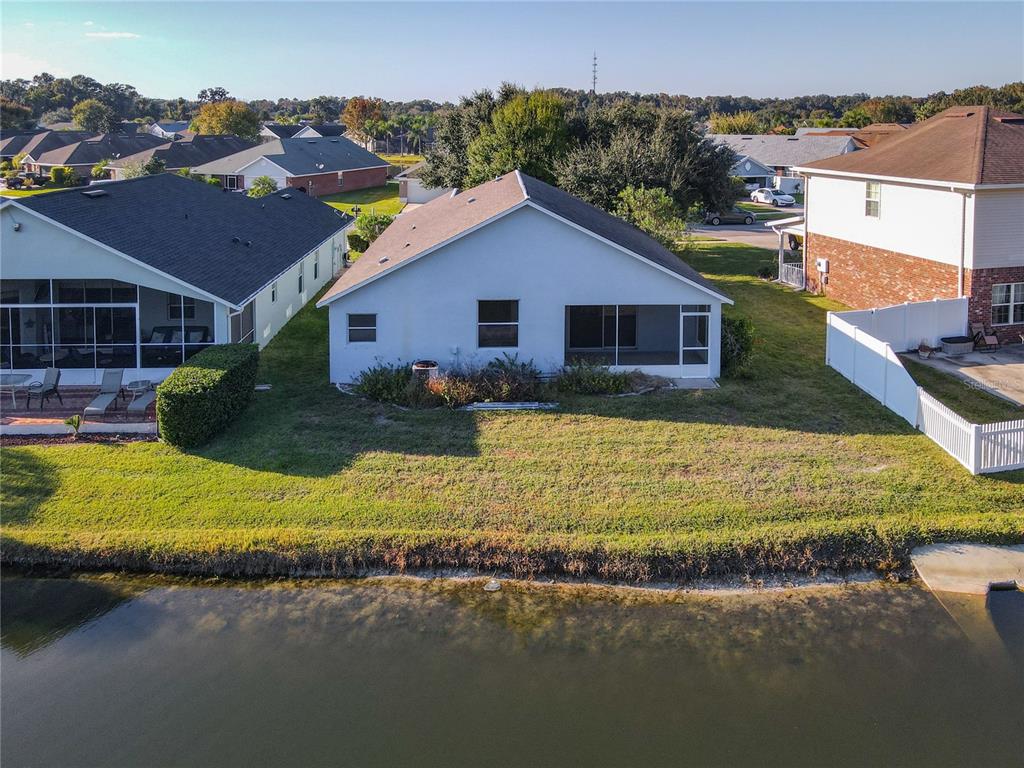 A rear view of a single-story house with a screened porch overlooking a lake — 530 CORAL TRACE BOULEVARD, EDGEWATER, FL