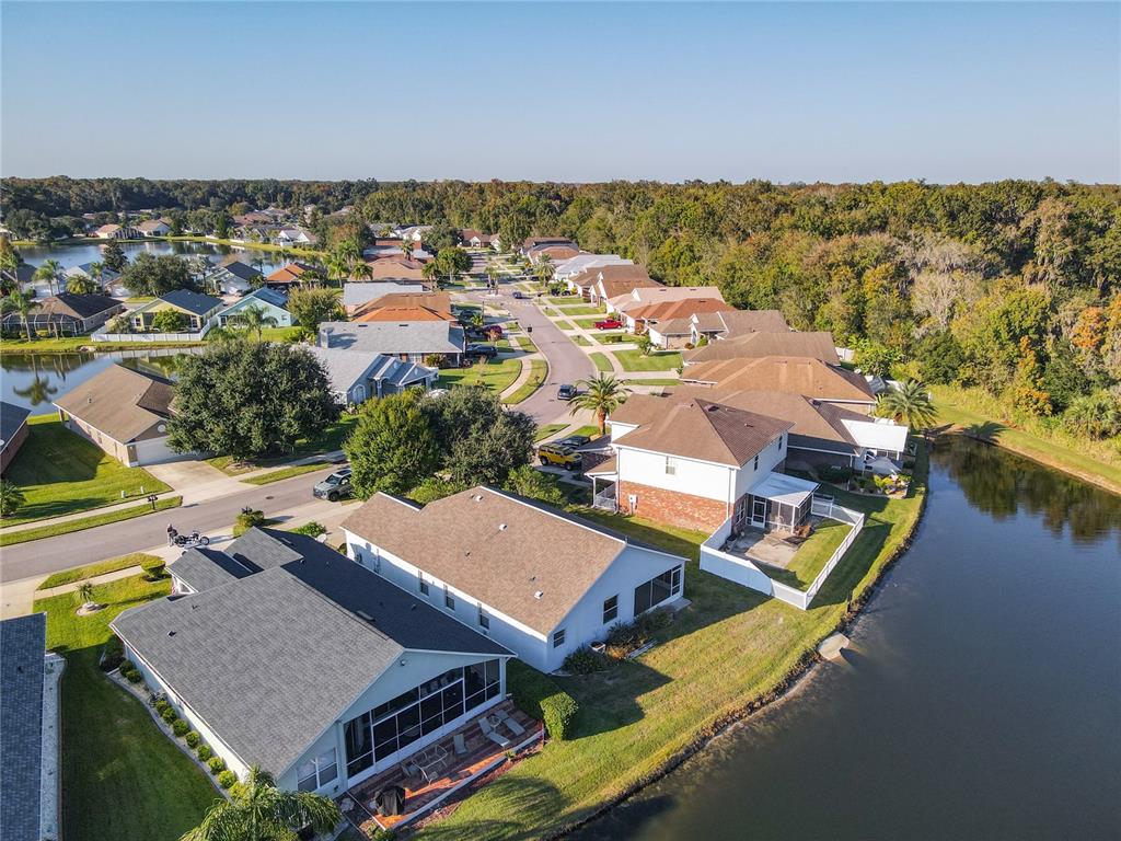An aerial view shows suburban houses with shingled roofs situated along a winding lake — 530 CORAL TRACE BOULEVARD, EDGEWATER, FL