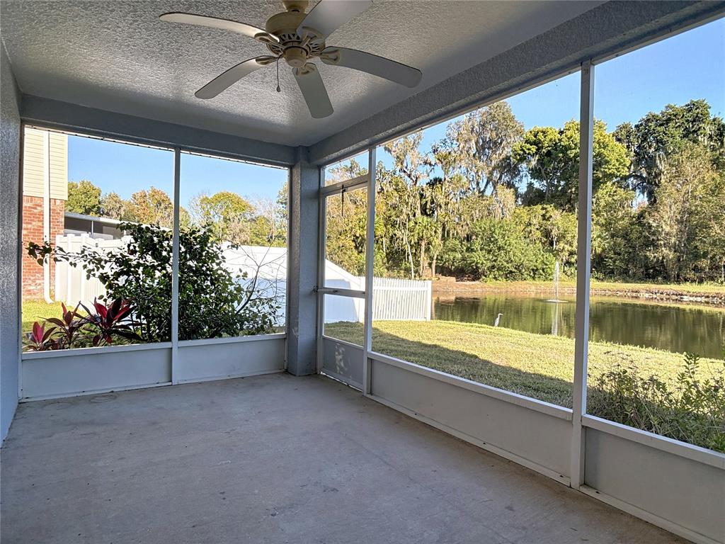A screened-in patio features a ceiling fan, concrete flooring, and a view of a pond — 530 CORAL TRACE BOULEVARD, EDGEWATER, FL