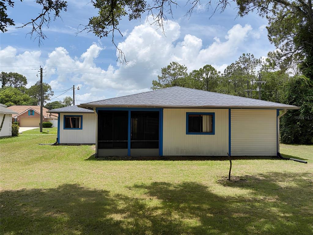 The exterior of a single-story house features a screened-in porch and a light-colored siding — 20 WOODBURY DRIVE, PALM COAST, FL