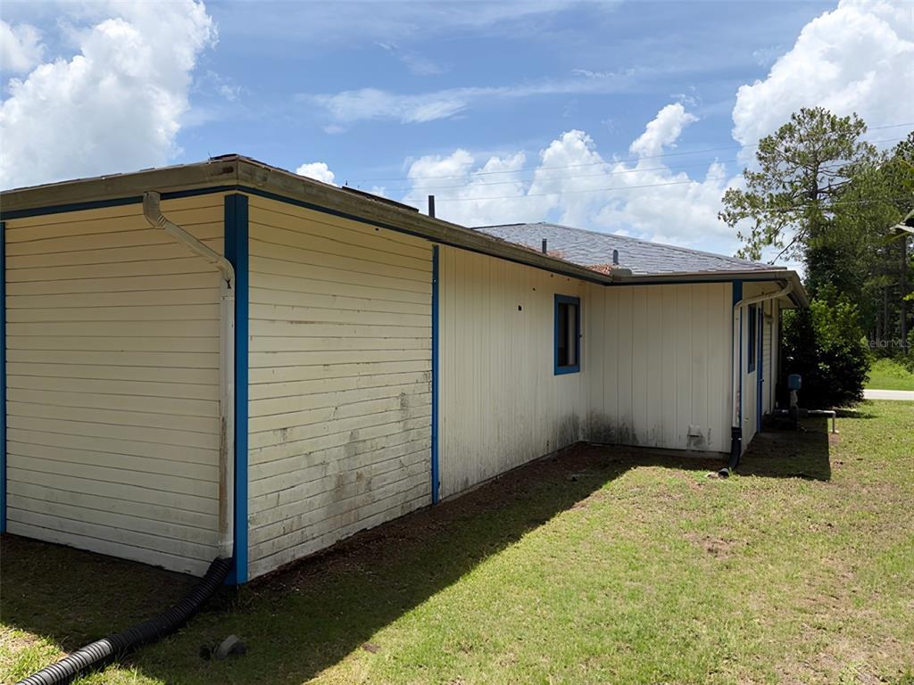 The exterior of a house features light-colored siding, blue trim, and a dark shingled roof — 20 WOODBURY DRIVE, PALM COAST, FL