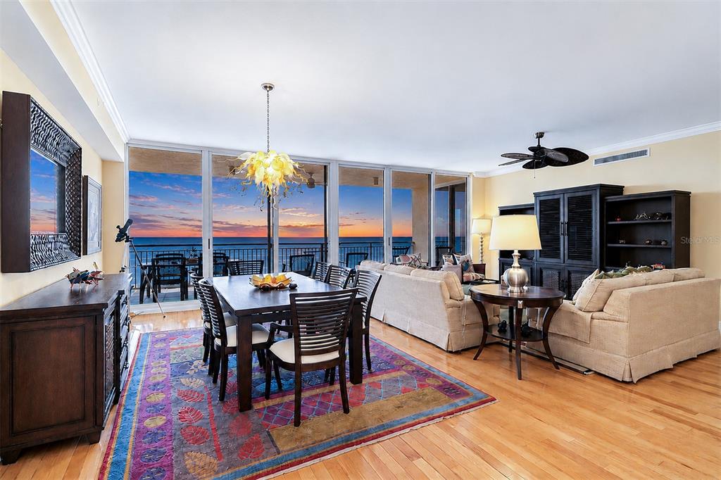 A dining and living area features hardwood floors, a colorful rug, and floor-to-ceiling ocean views — 15208 GULF BOULEVARD UNIT 404, MADEIRA BEACH, FL