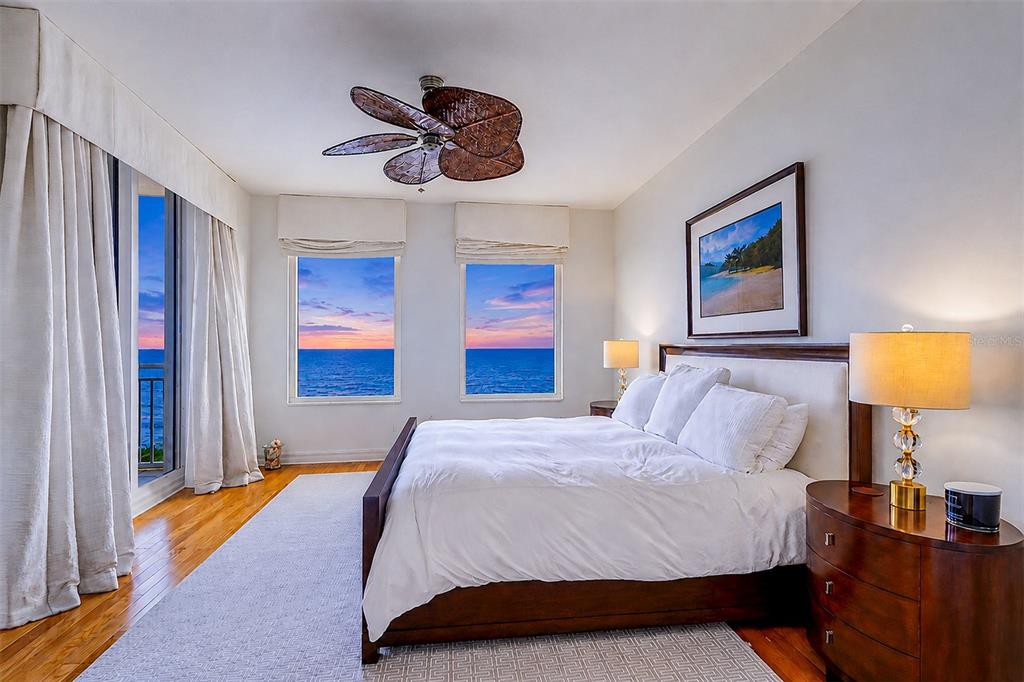 A bedroom features a king bed, ocean views through windows and a balcony, and a fan — 15208 GULF BOULEVARD UNIT 404, MADEIRA BEACH, FL
