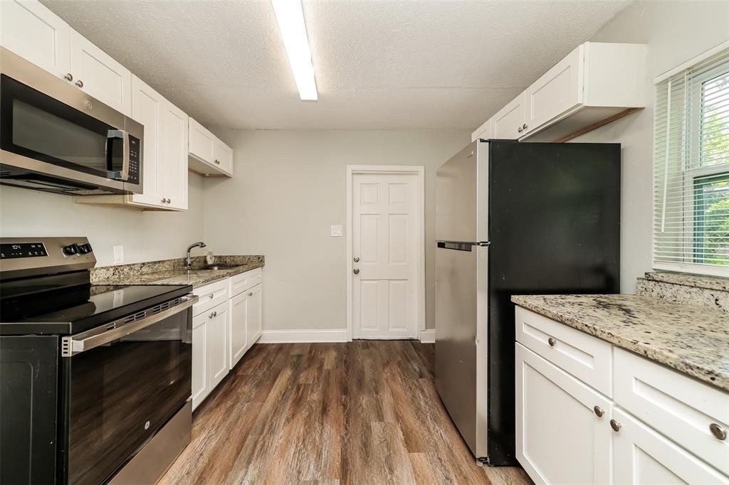 A kitchen features white cabinets, granite countertops, stainless steel appliances, and wood-look flooring — 2624 13TH AVENUE S, ST PETERSBURG, FL