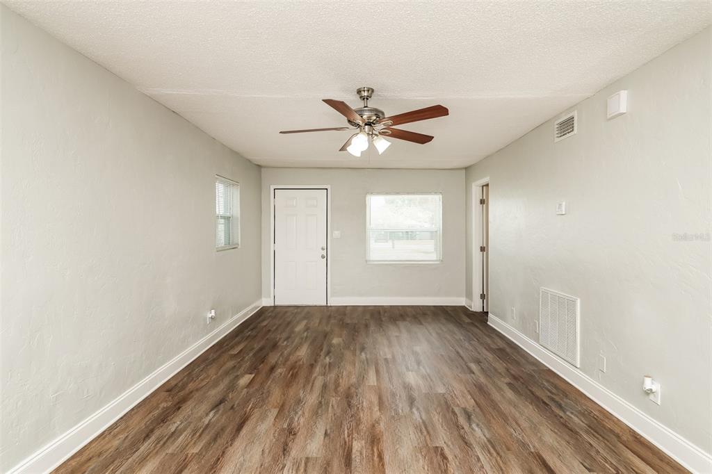 An empty room with light gray walls, wood-look flooring, a ceiling fan, and a white door — 2624 13TH AVENUE S, ST PETERSBURG, FL