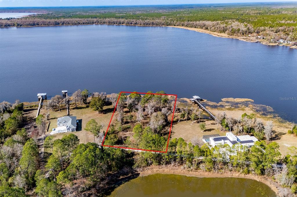 An aerial view shows a vacant, tree-covered lot outlined in red along a lakefront — LAKESHORE DRIVE, STARKE, FL
