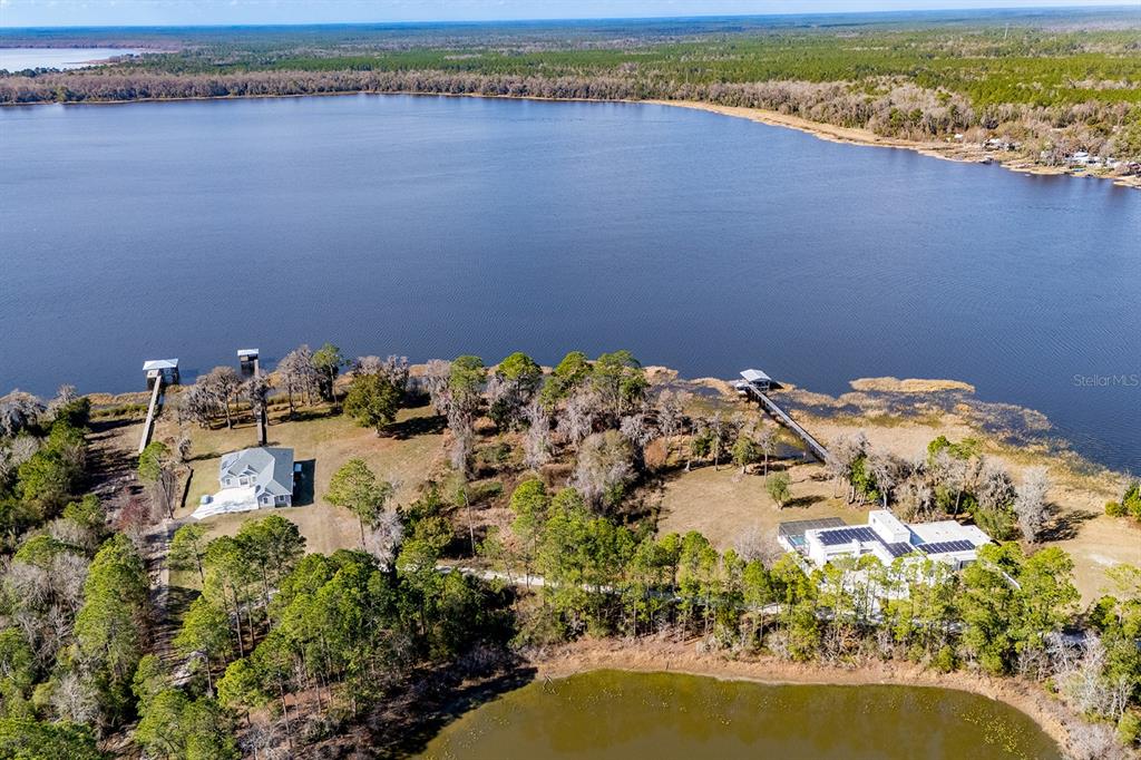 An aerial view shows two houses situated on a lakefront property with private docks — LAKESHORE DRIVE, STARKE, FL