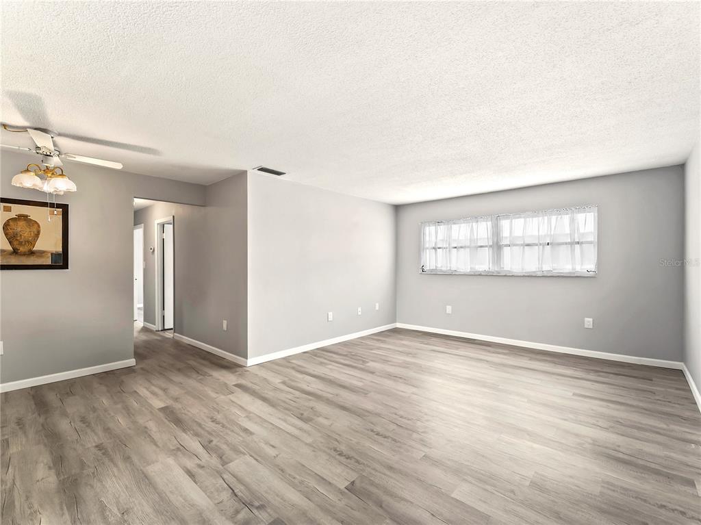 An empty living room features light gray walls, wood-look flooring, and a ceiling fan — 460 BASE AVENUE E UNIT 128, VENICE, FL