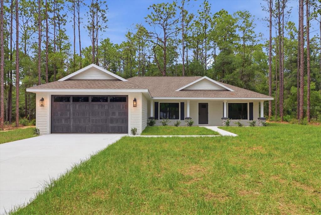 A single-story house with a two-car garage, white siding, and a covered front porch — 1683 W PEARSON STREET, HERNANDO, FL