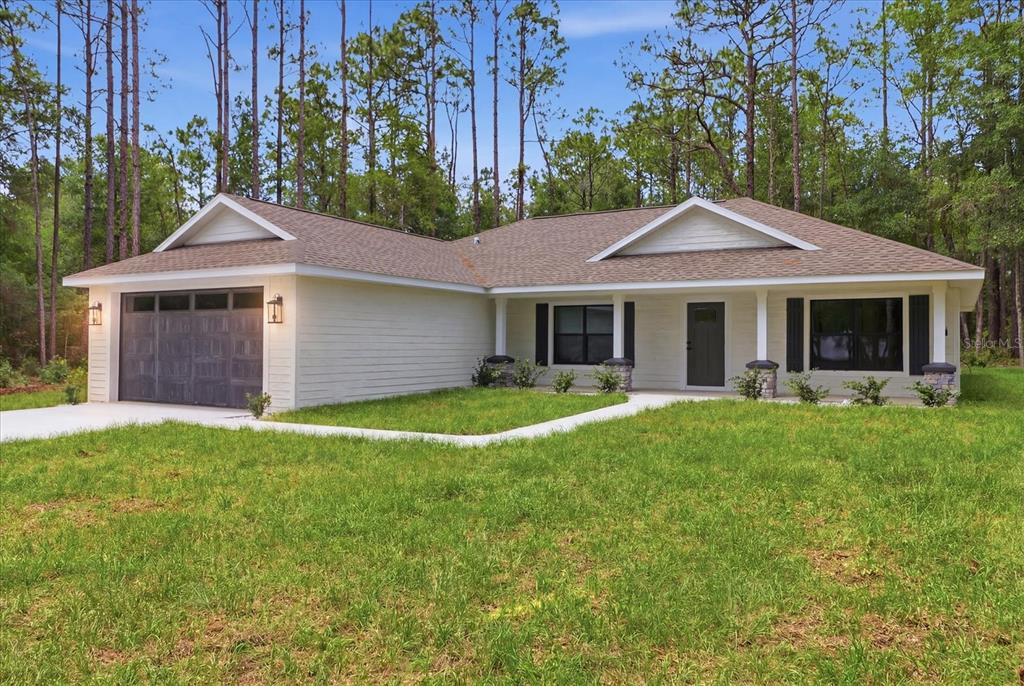 A single-story house with white siding, a dark garage door, and a front porch — 1683 W PEARSON STREET, HERNANDO, FL