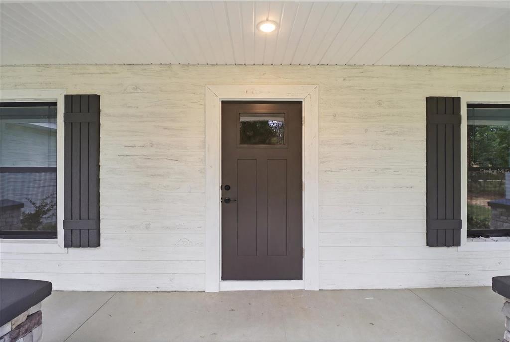 A front porch features a dark brown door with a window and dark shutters — 1683 W PEARSON STREET, HERNANDO, FL