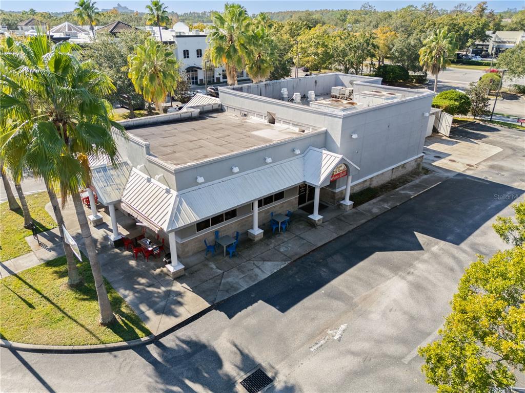 An aerial view shows a commercial building with a gray exterior and outdoor patio seating — 8841 COMMODITY CIRCLE, ORLANDO, FL