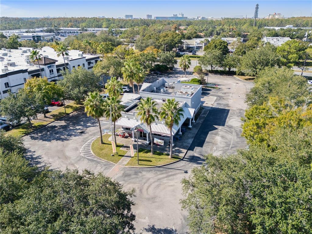 An aerial view shows a commercial building with a parking lot and surrounding palm trees — 8841 COMMODITY CIRCLE, ORLANDO, FL