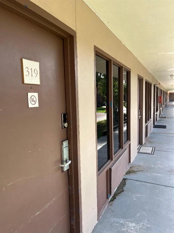 An exterior view of a brown door labeled 319 next to a windowed wall — 8421 S ORANGE BLOSSOM TRAIL UNIT 319, ORLANDO, FL