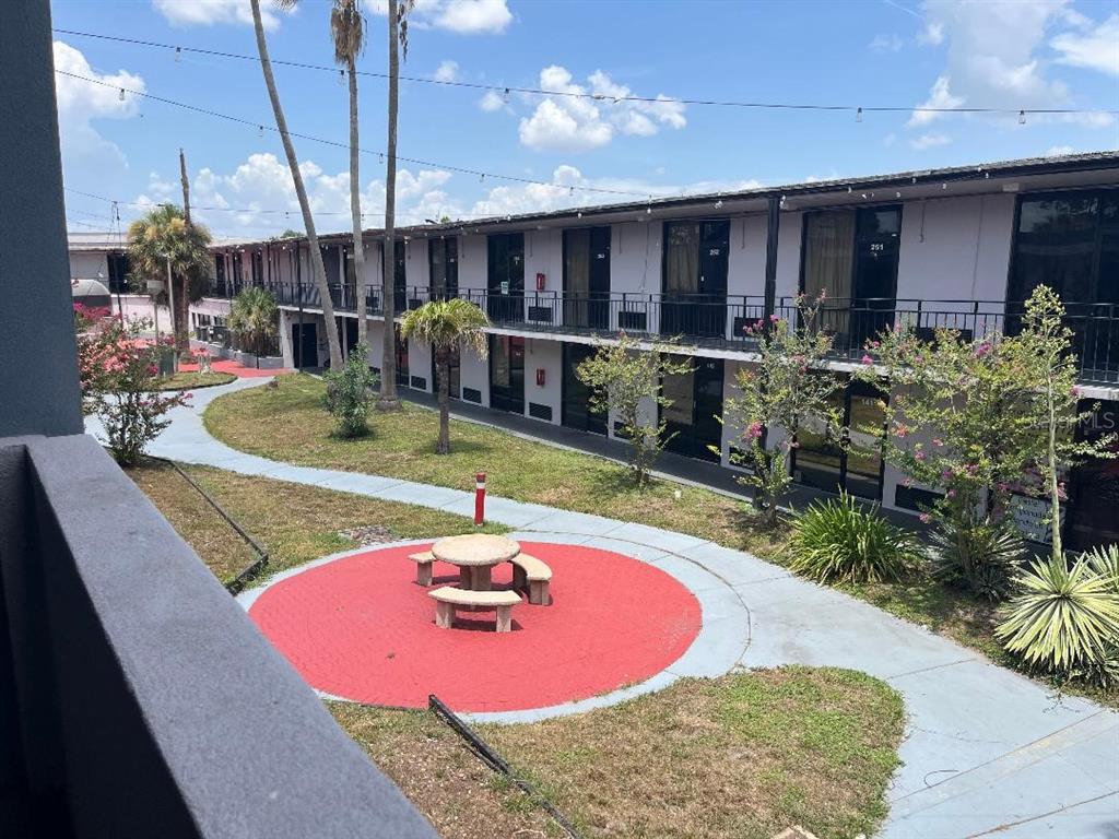 An exterior view of a two-story motel with a central courtyard and picnic table — 8421 S ORANGE BLOSSOM TRAIL UNIT 319, ORLANDO, FL