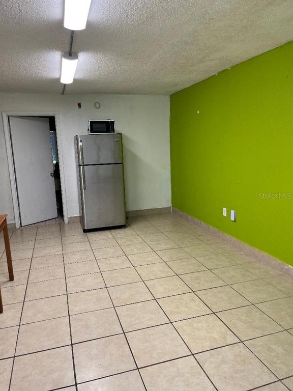 A kitchen area features a stainless steel refrigerator, tile flooring, and a bright green wall — 8421 S ORANGE BLOSSOM TRAIL UNIT 319, ORLANDO, FL