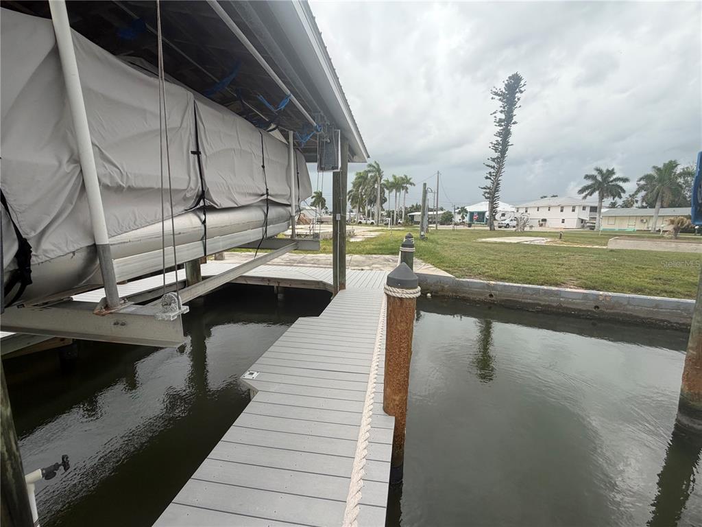 A boat lift with a covered boat sits beside a gray dock on a canal — 3881 ARECA DRIVE, ST JAMES CITY, FL