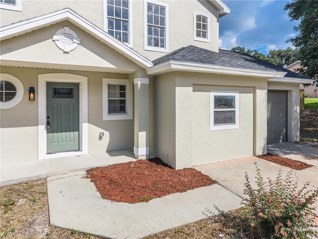 The exterior of a two-story house features a green front door and a concrete driveway — 11424 MANDARIN DRIVE, CLERMONT, FL