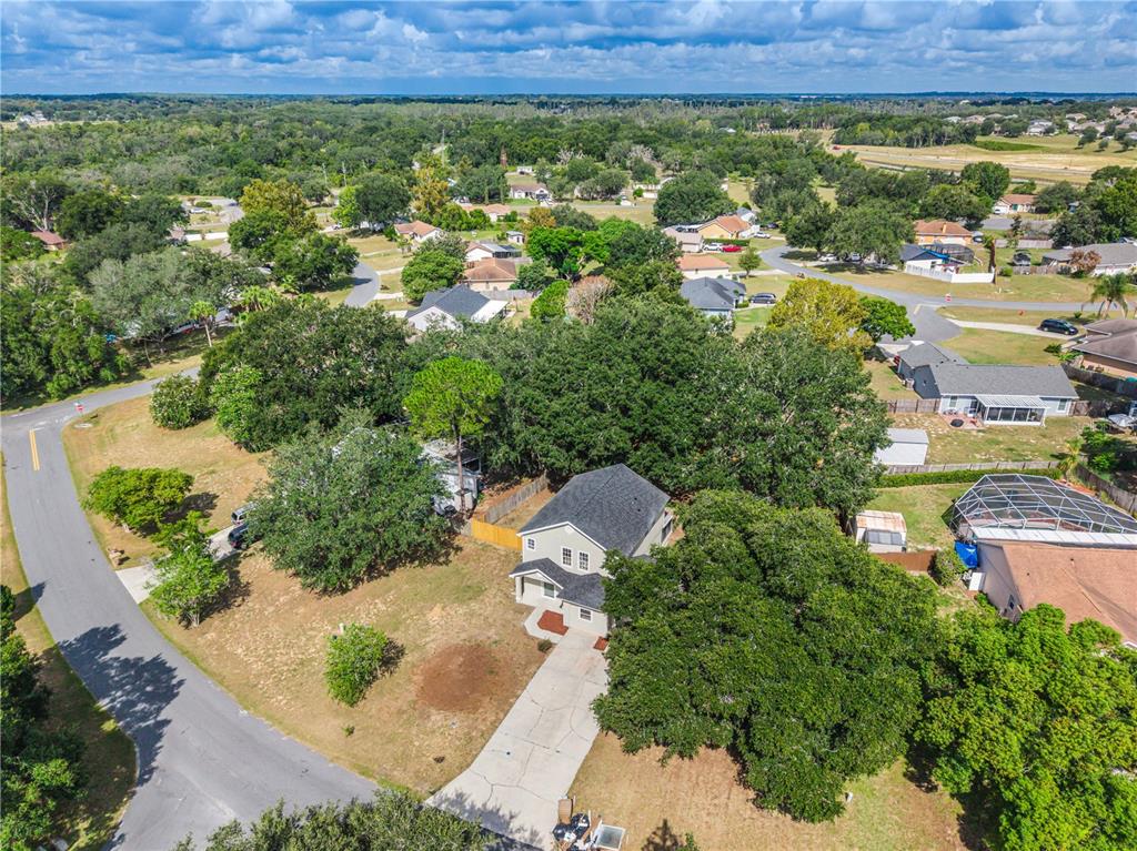 An aerial view shows a two-story house with a driveway surrounded by mature trees — 11424 MANDARIN DRIVE, CLERMONT, FL