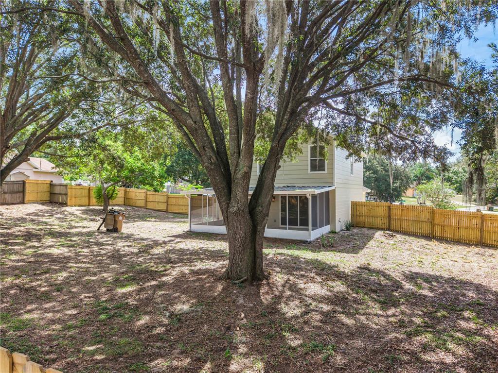 A two-story house with a screened-in porch sits in a large yard with mature trees — 11424 MANDARIN DRIVE, CLERMONT, FL