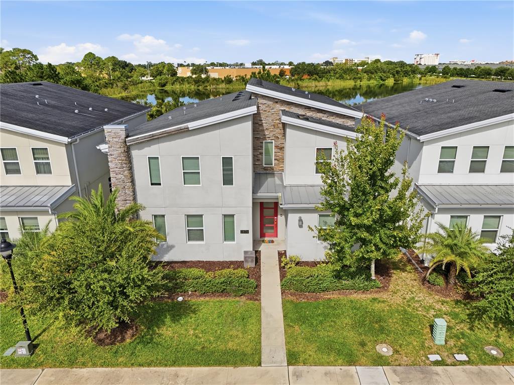 An exterior view of a modern two-story townhouse with a red front door and stone accents — 2874 STANZA COURT, KISSIMMEE, FL