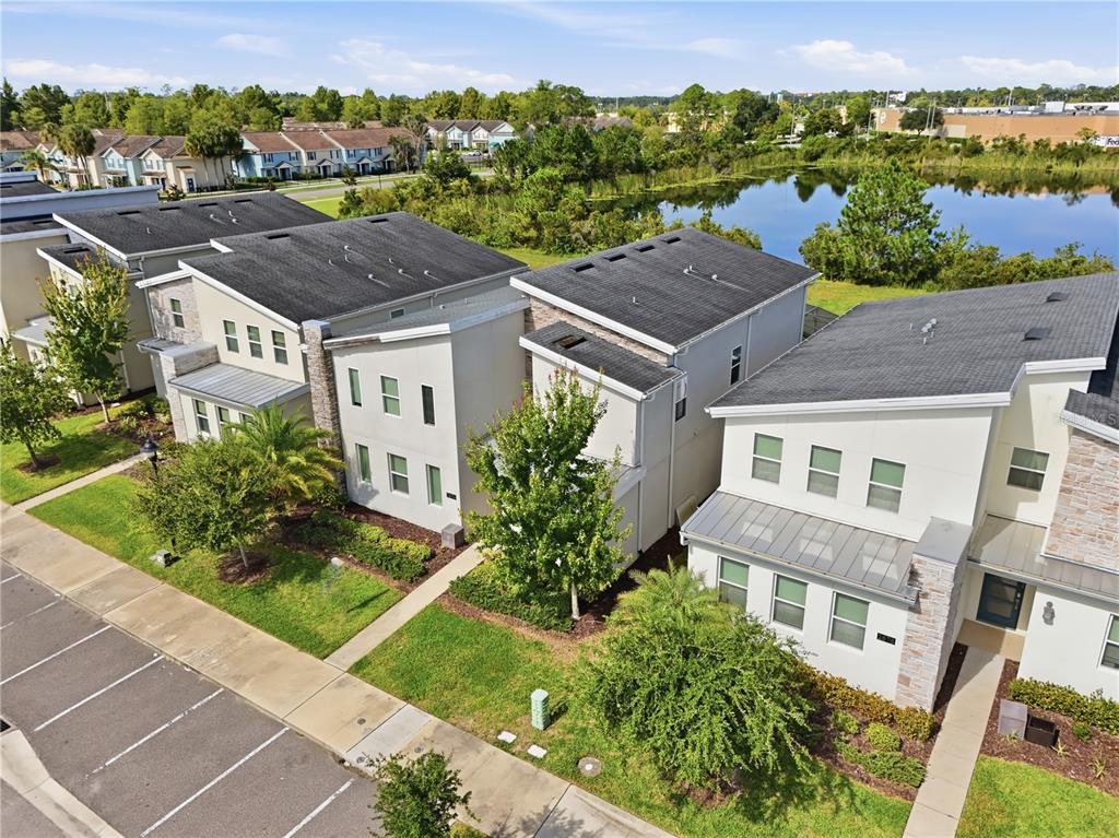An aerial view shows a row of modern townhouses with parking spaces and a pond — 2874 STANZA COURT, KISSIMMEE, FL