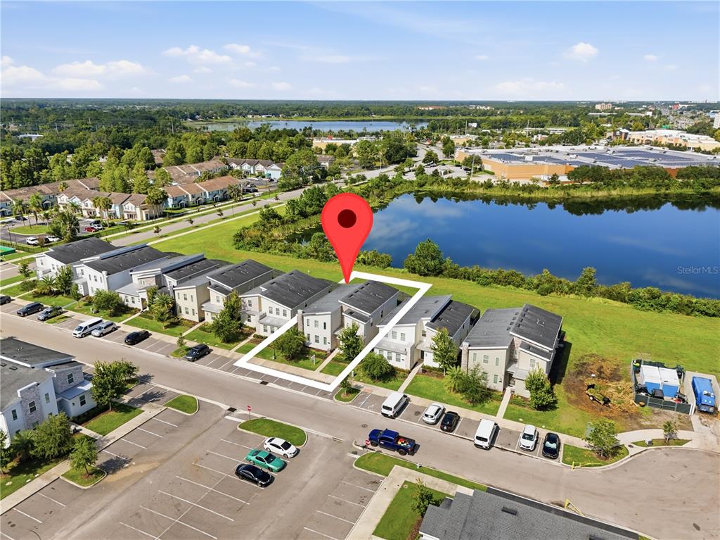 An aerial view shows a row of modern townhomes situated next to a large pond — 2874 STANZA COURT, KISSIMMEE, FL