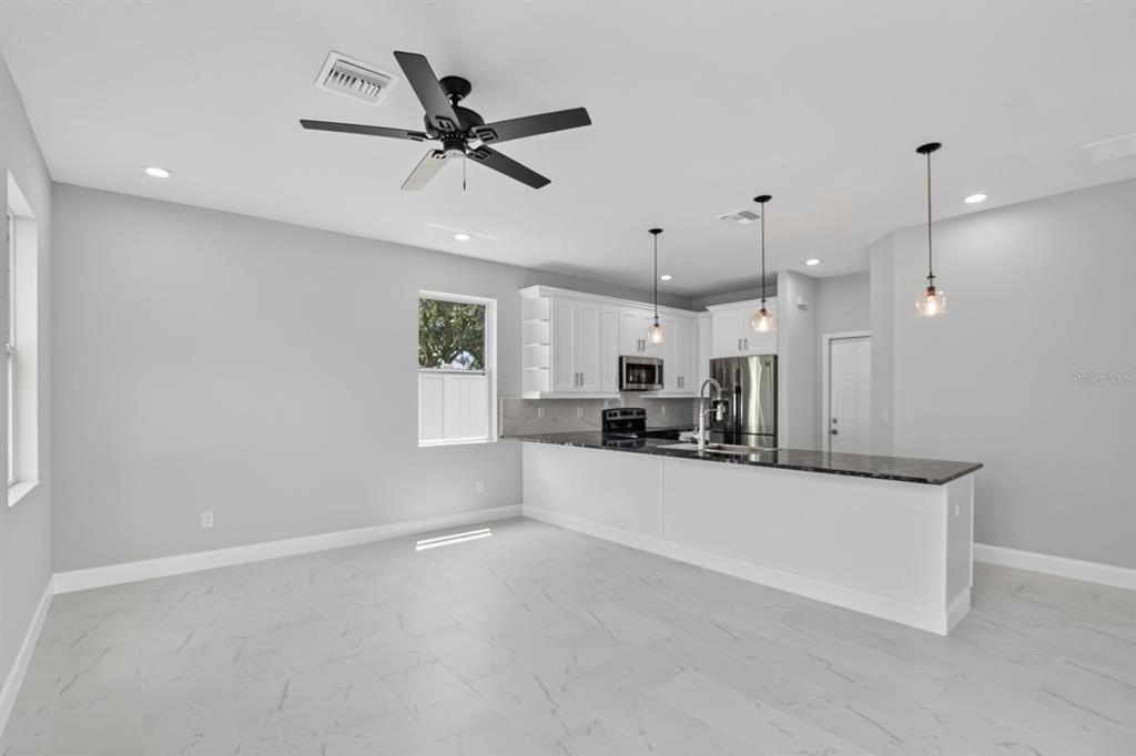 A kitchen with white cabinets, dark countertops, and light tile flooring in an open space — 11521 HIGDON DRIVE, THONOTOSASSA, FL