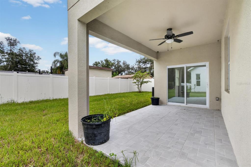 A covered patio with light-colored pavers, a ceiling fan, and a view of the backyard — 11521 HIGDON DRIVE, THONOTOSASSA, FL