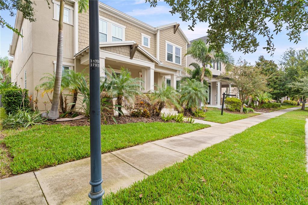 A multi-story residential building with tan siding, a covered porch, and palm trees in front — 5955 CALDERA RIDGE DRIVE, LITHIA, FL