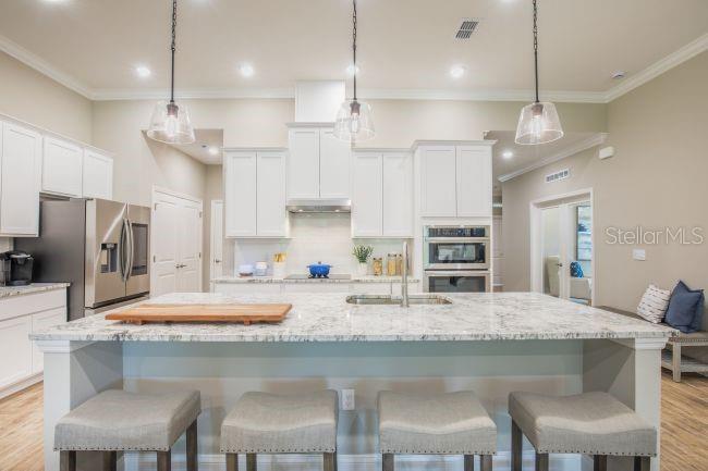 A modern kitchen features white cabinets, a large granite island, and four upholstered bar stools — TBD OLD SQUAW AVENUE, WEEKI WACHEE, FL