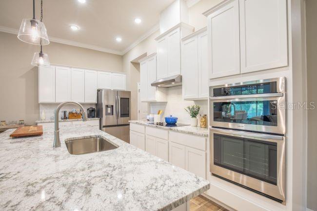 A modern kitchen features white cabinets, granite countertops, a large island, and stainless steel appliances — TBD OLD SQUAW AVENUE, WEEKI WACHEE, FL
