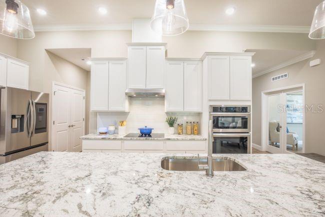 A modern kitchen features white cabinetry, granite countertops, a large island, and stainless steel appliances — TBD OLD SQUAW AVENUE, WEEKI WACHEE, FL