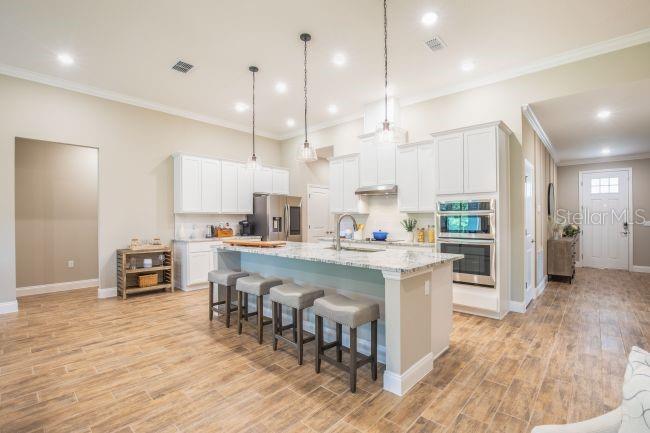A kitchen with white cabinets, a granite-topped island with stools, and wood-look tile flooring — TBD OLD SQUAW AVENUE, WEEKI WACHEE, FL