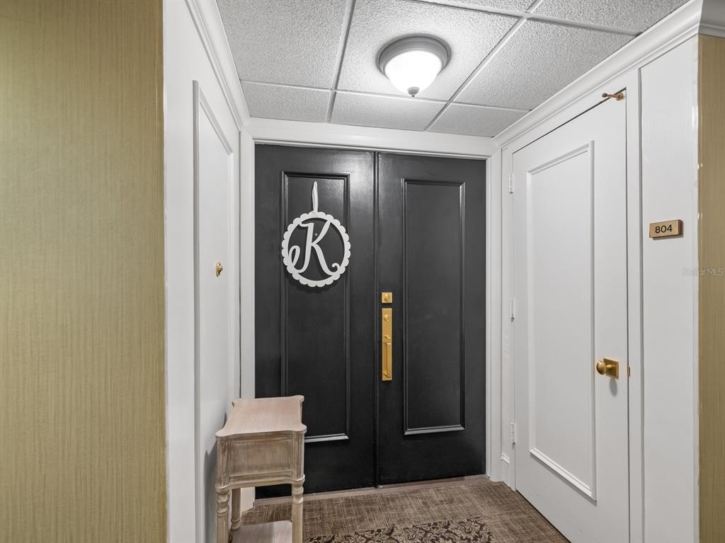 A hallway features a black double door with a monogram wreath and a small table — 4 BELLEVIEW BOULEVARD UNIT 804, BELLEAIR, FL