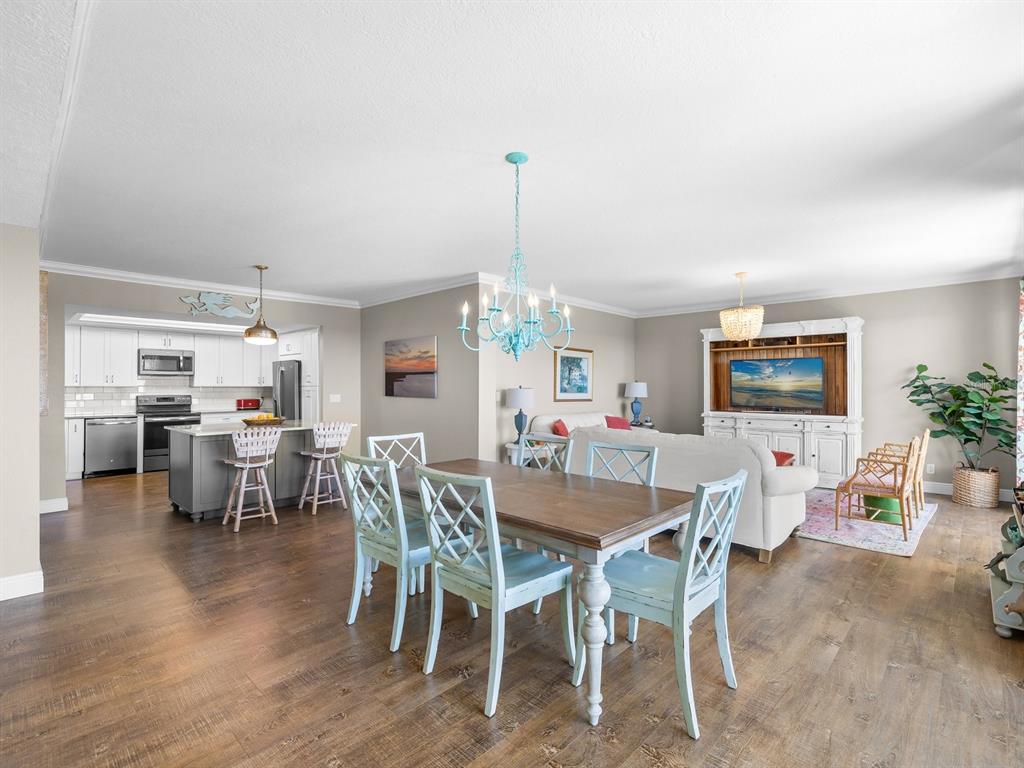 An open-concept living and dining area features light blue chairs, wood flooring, and a kitchen — 4 BELLEVIEW BOULEVARD UNIT 804, BELLEAIR, FL