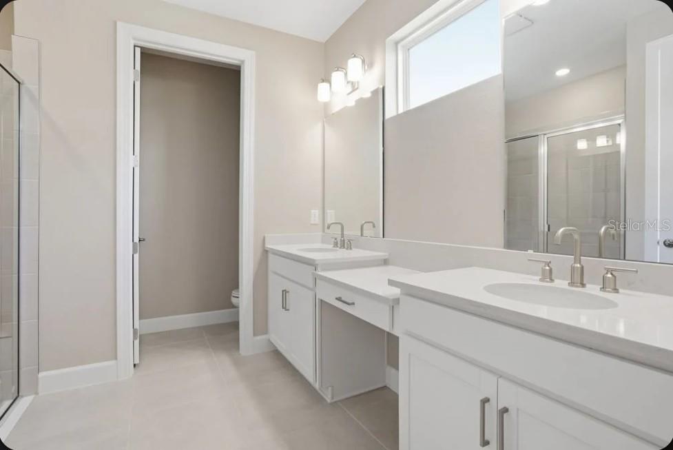 A bathroom with a double vanity, white cabinets, quartz countertops, and a separate toilet room — 7824 CASPIAN STREET, PALMETTO, FL