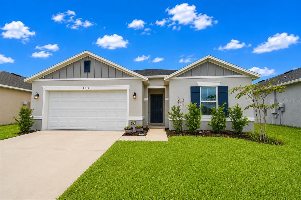 A single-story house with a two-car garage, gray siding, and a green lawn — 2817 WOODACRE DRIVE, HAINES CITY, FL
