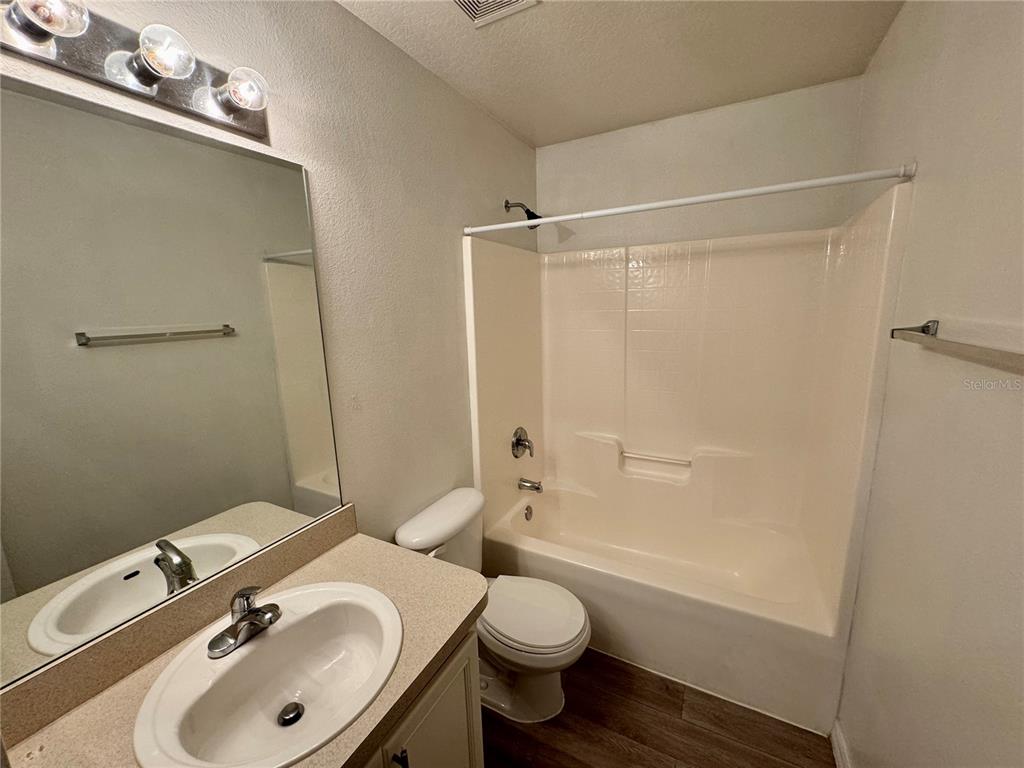 A bathroom features a vanity with a sink, a toilet, and a shower-tub combination — 1011 MORVAN LANE, KISSIMMEE, FL