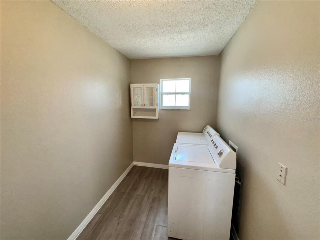 A laundry room with a white washer and dryer, wood-look flooring, and a wall cabinet — 1011 MORVAN LANE, KISSIMMEE, FL