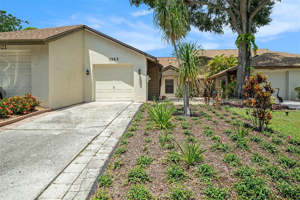 A single-story residential building with a concrete driveway, garage, and landscaped front yard — 1923 BAYSHORE COURT, SAFETY HARBOR, FL