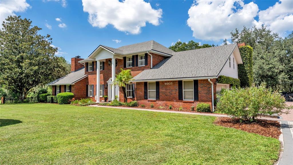 A two-story brick house with a white columned portico and a large front lawn — 6605 POLEY CREEK DRIVE W, LAKELAND, FL