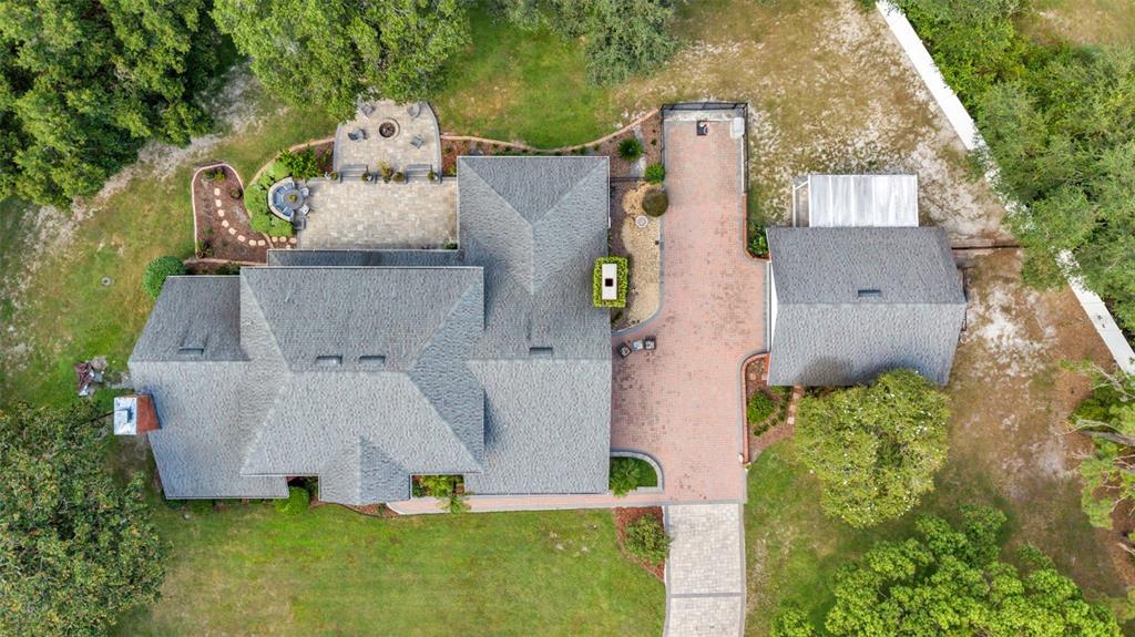 An aerial view shows a house with a gray shingled roof, brick driveway, and patio — 6605 POLEY CREEK DRIVE W, LAKELAND, FL