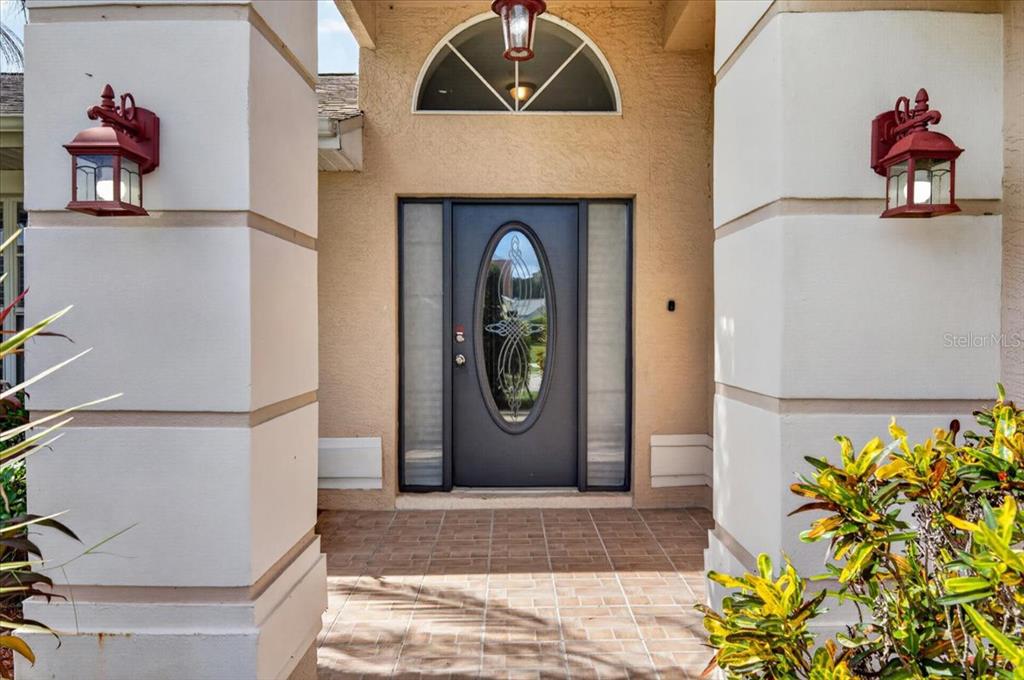 A front entryway features a dark gray door with an oval glass insert and sidelights — 854 CHRISTINA CIRCLE, OLDSMAR, FL