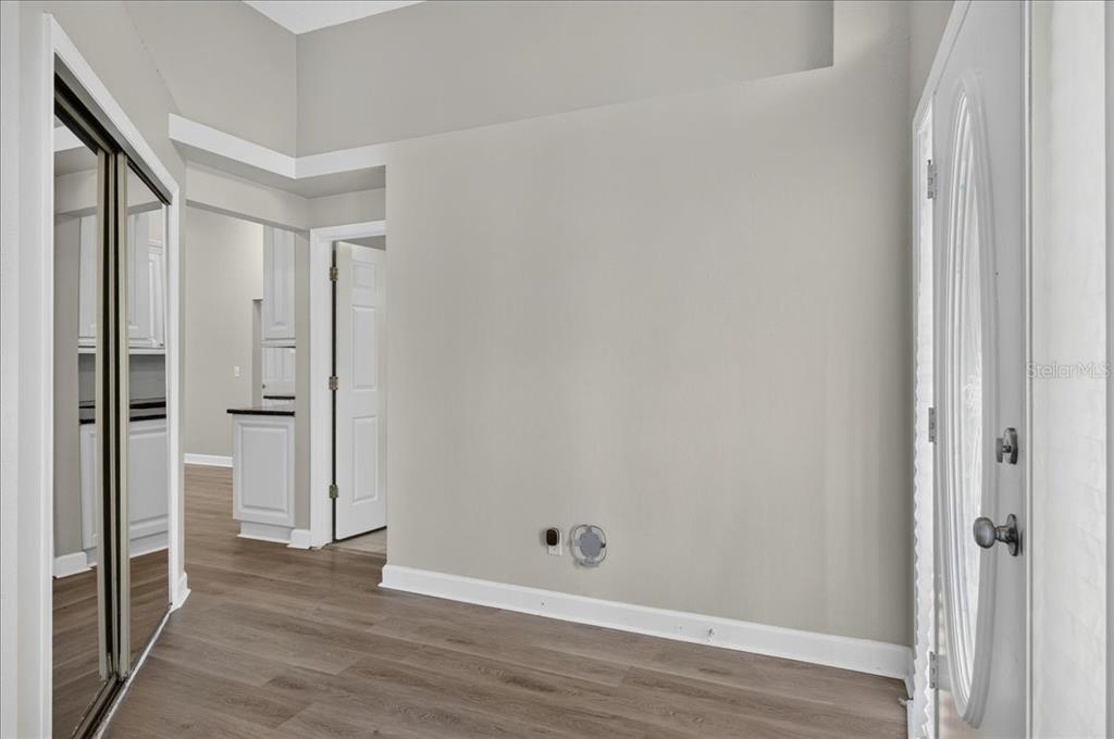 An entryway features light gray walls, wood-look flooring, a mirrored closet, and a white door — 854 CHRISTINA CIRCLE, OLDSMAR, FL