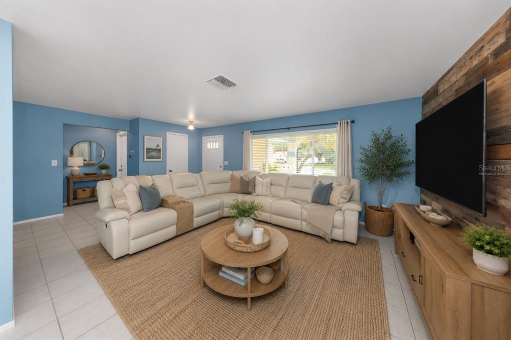 A living room features a large white sectional sofa, a wooden coffee table, and blue walls — 9237 AMAZON DRIVE, NEW PORT RICHEY, FL