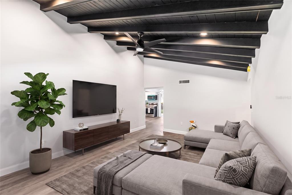 A living room features a vaulted ceiling with dark exposed beams, a sectional sofa, and television — 420 MELODY CIRCLE, SARASOTA, FL
