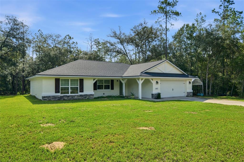 A single-story house with a white exterior, stone accents, and a two-car garage — 8683 N TEATHER TERRACE, CITRUS SPRINGS, FL