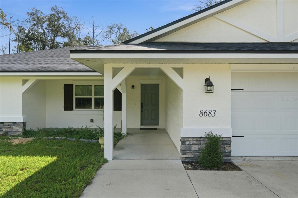 The exterior of a single-story house features a covered entryway, stone accents, and a garage — 8683 N TEATHER TERRACE, CITRUS SPRINGS, FL